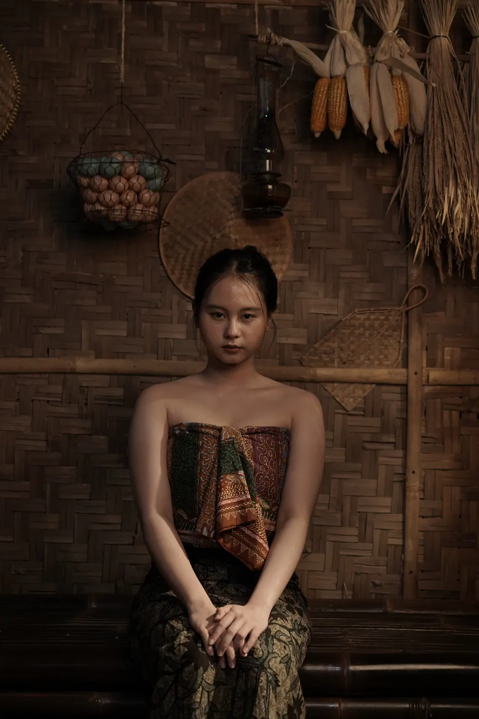 Portrait tematik tradisional: perempuan berkemben duduk di dalam rumah bambu, foto oleh Doeng