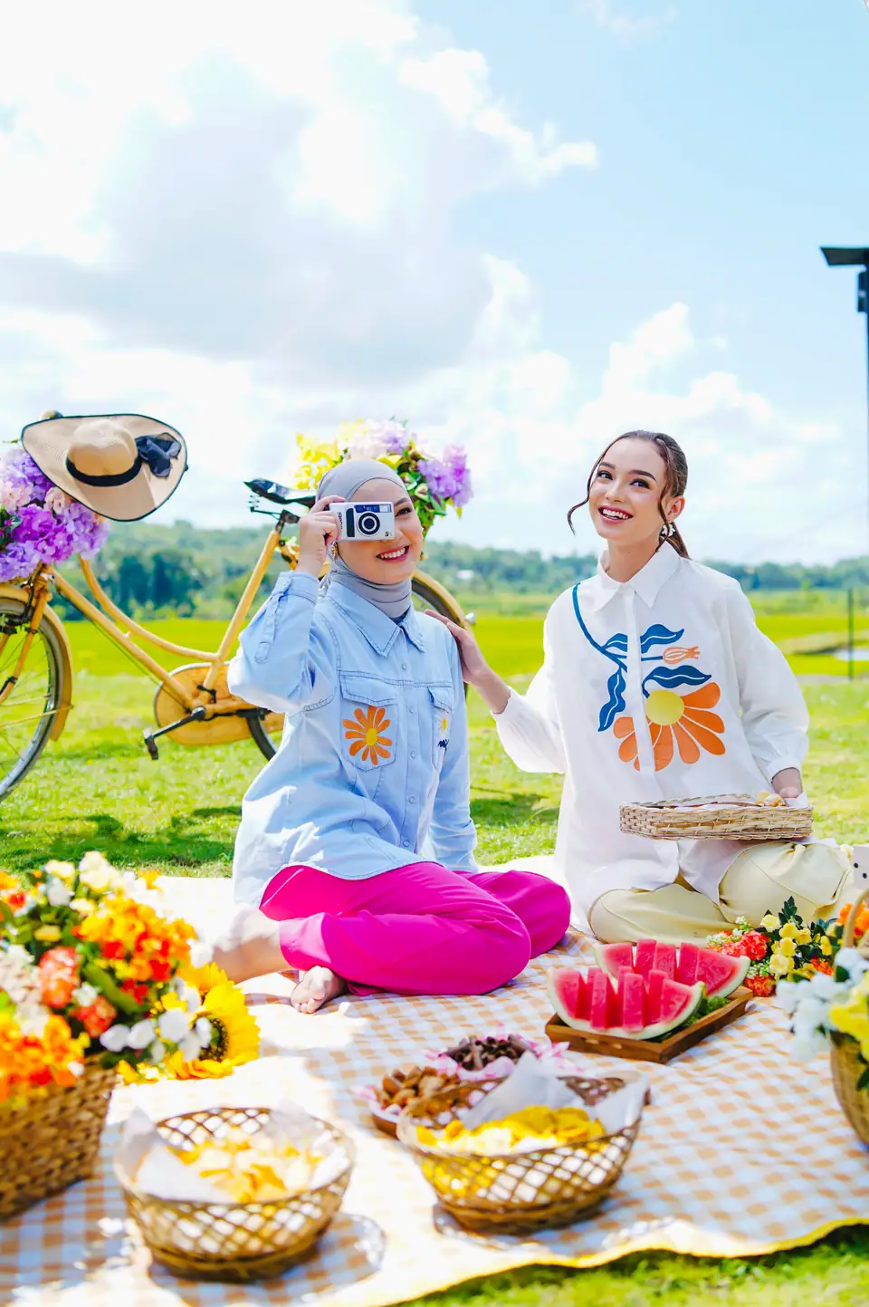 Foto konsep piknik: dua perempuan bergaya di taman dengan sepeda dan hidangan buah, foto oleh Huda