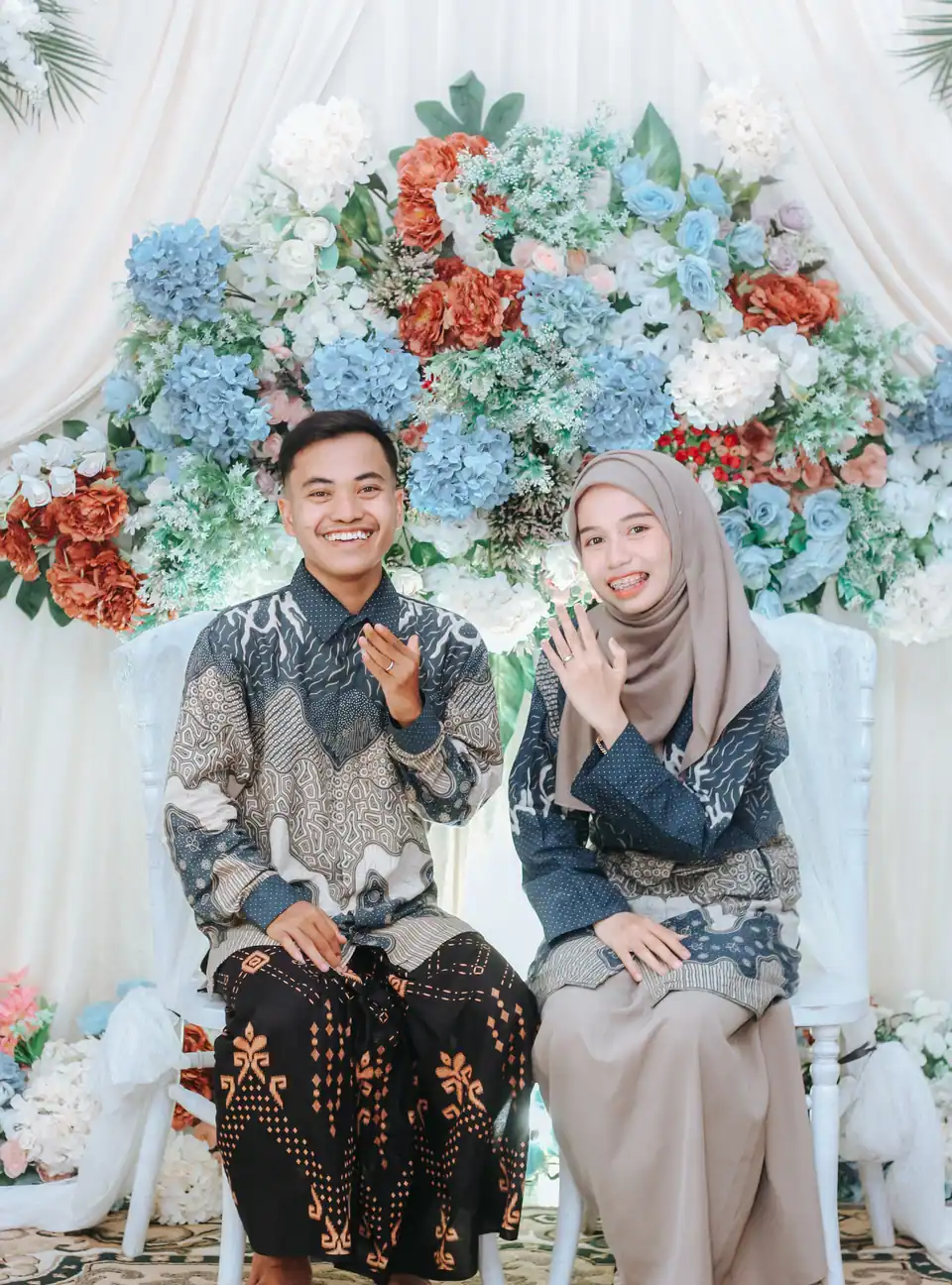 Foto pernikahan: pasangan pengantin berbatik di pelaminan bunga, foto oleh Jeghout Visualworks