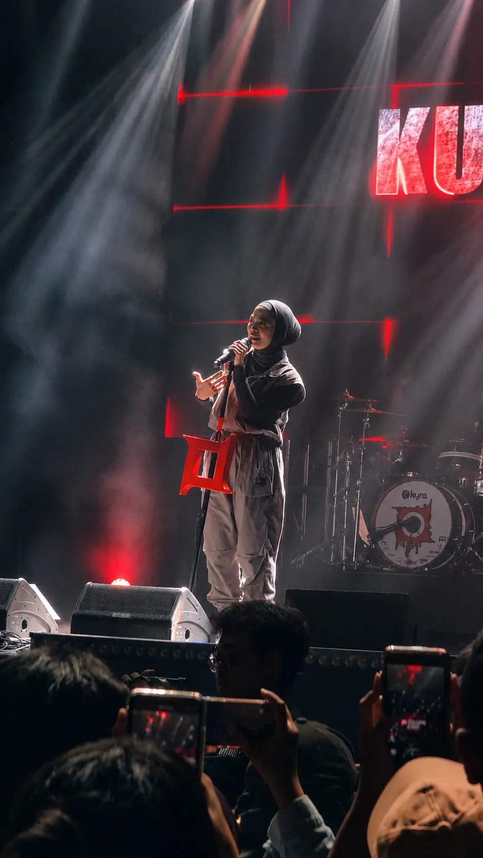 Foto konser: vokalis tampil di bawah sorot lampu merah dan asap, foto oleh Mario