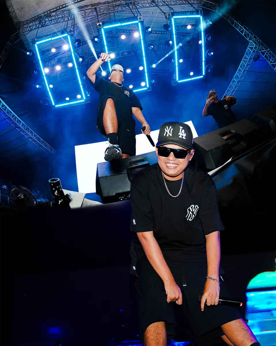 Foto konser: rapper bertopi tampil di depan lampu panggung biru, foto oleh Rifqi