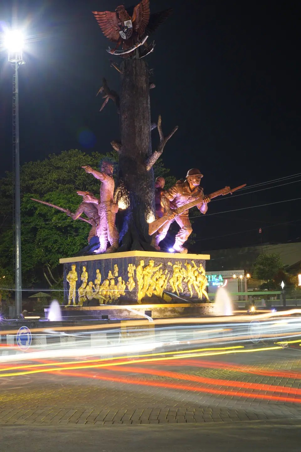 Foto malam monumen kota dengan jejak cahaya kendaraan hasil teknik long exposure, foto oleh Usman